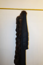 Brown fur-trimmed jackets/cardigan on a rack against a white wall.
