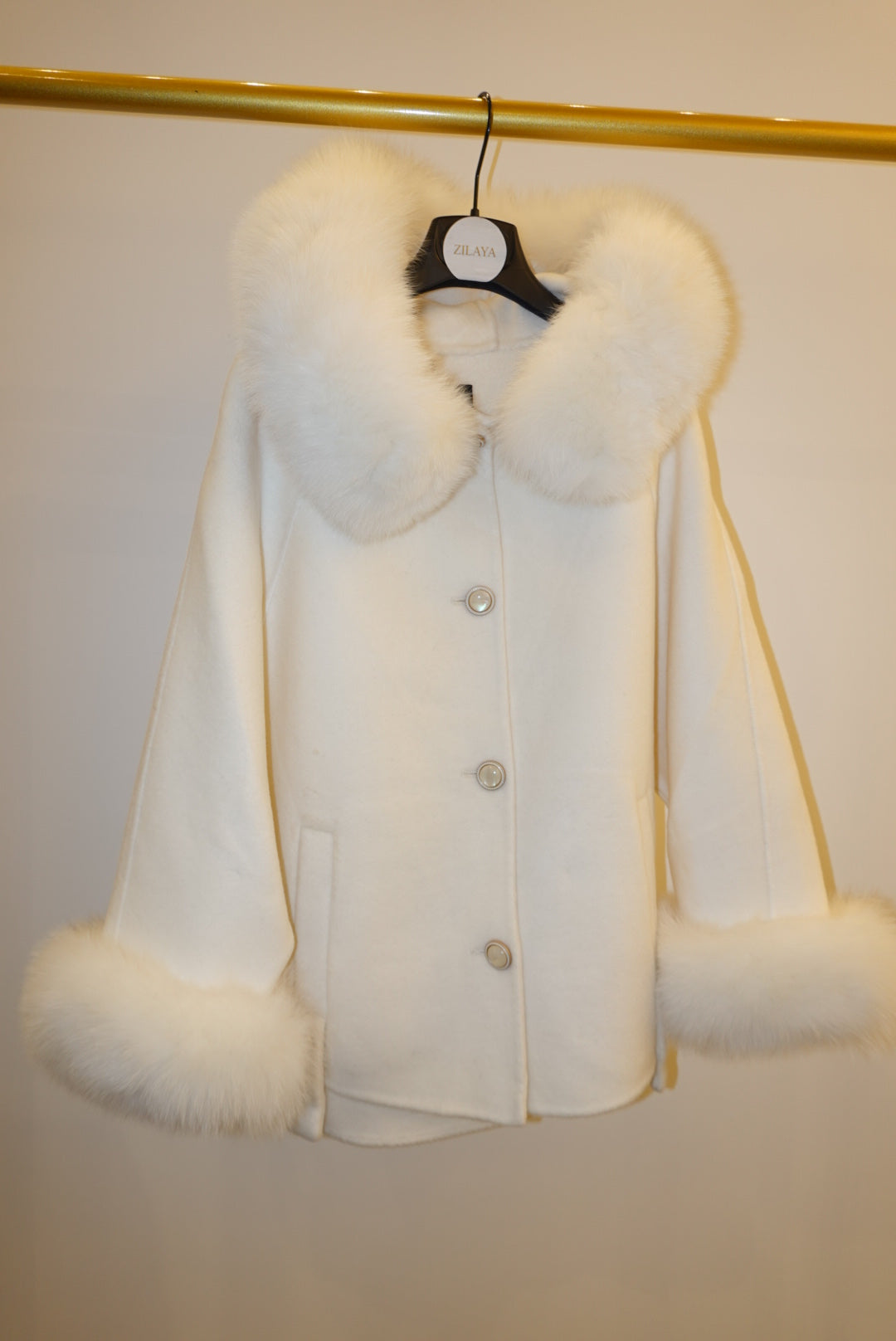 White fur coat with hood against a plain background
