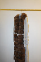 Brown fur-trimmed jackets/cardigan on a rack against a white wall.
