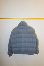 White and gray striped bomber jacket on a hanger against a white background