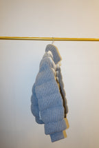 White and gray striped bomber jacket on a hanger against a white background