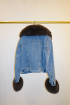 Blue denim jacket with brown fur trim on a white background