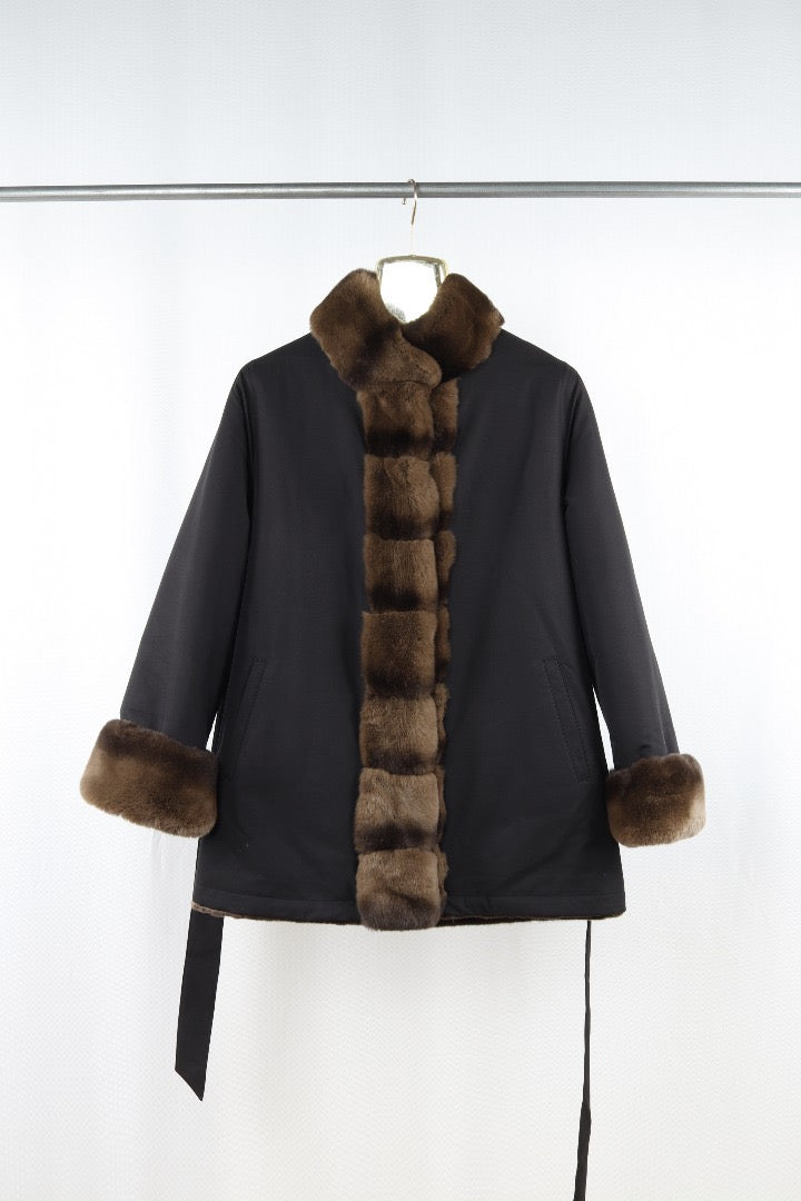 Black coat with fur trim on a hanger against a white background