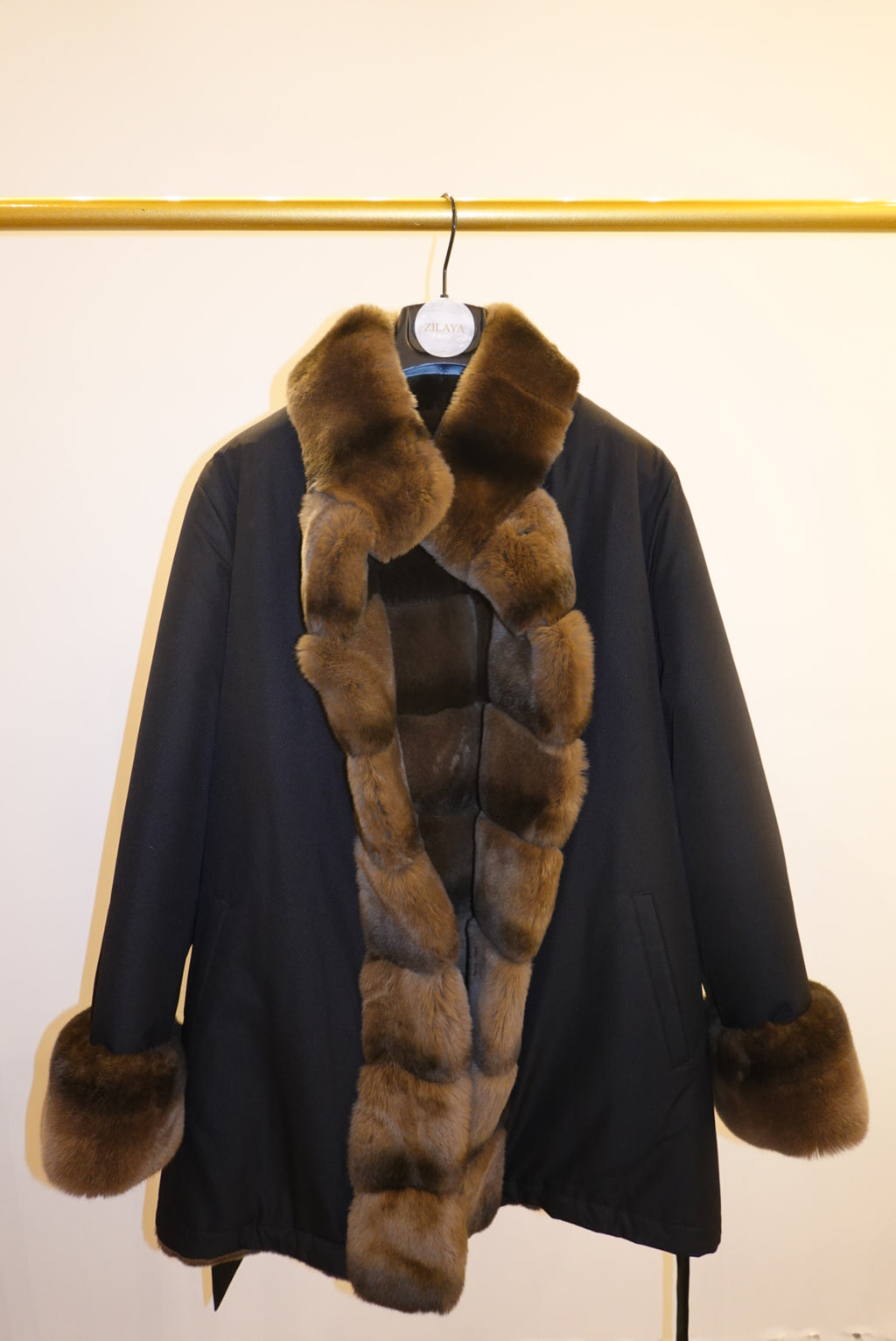 Black coat with brown fur trim against a white background
