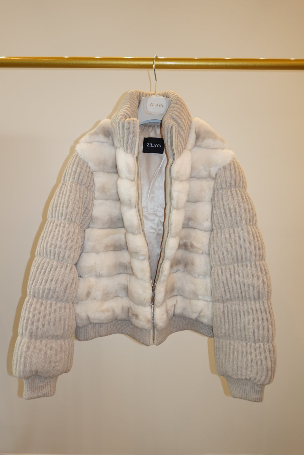 White and beige striped bomber jacket on a hanger against a white background